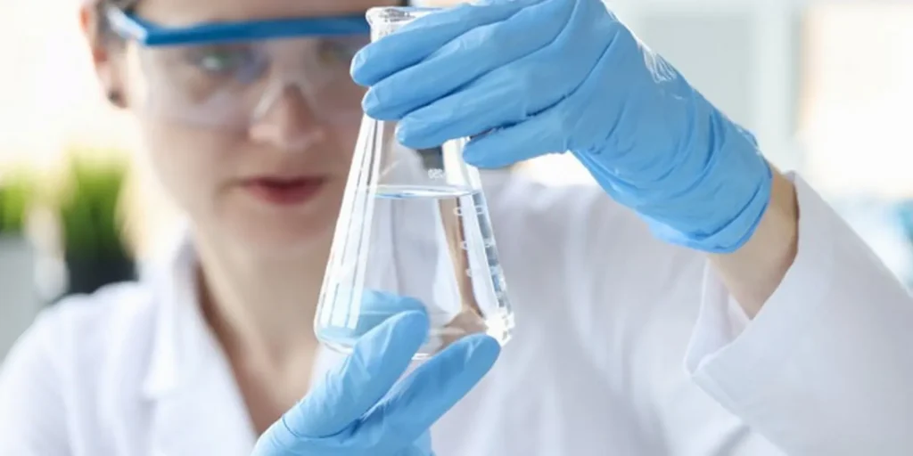 Mujer sosteniendo frasco de agua purificada. Artículo sobre las diferencias del agua purificada, destilada y filtrada